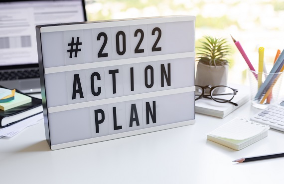 the words 2022 action plan spelled out on a light box on a desk with computer