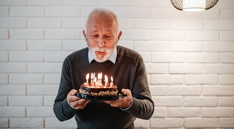 Men blowing out candles on a birthday cake.