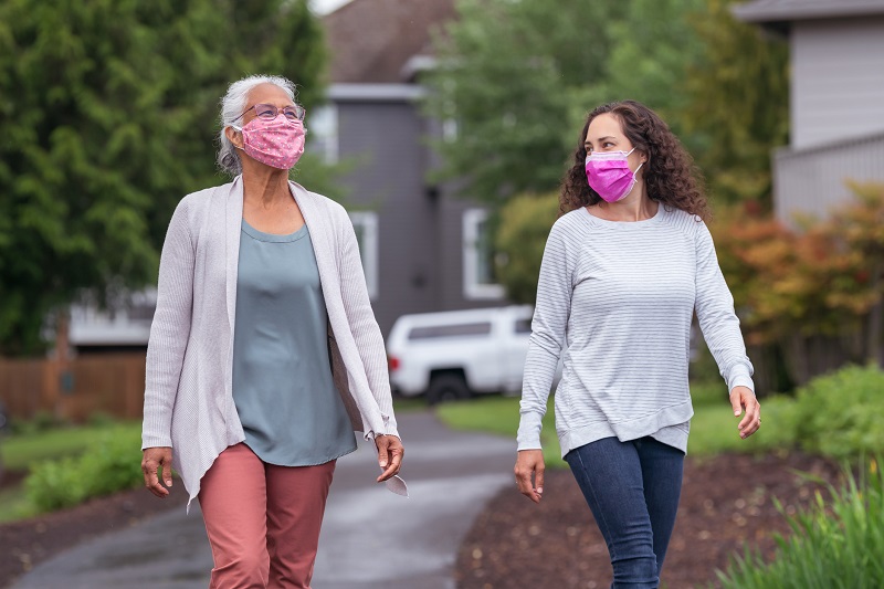 two women walking together while wearing face masks