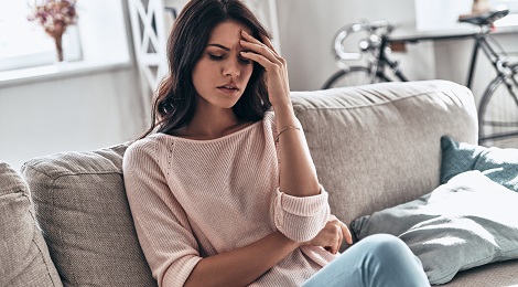 young woman sitting on couch with her hand on her face