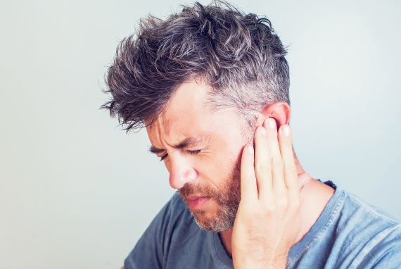 photo of a man touching his ear in pain