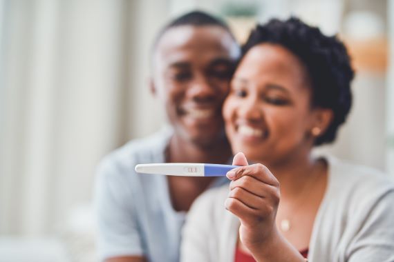 photo of a couple looking at a positive pregnancy test and smiling