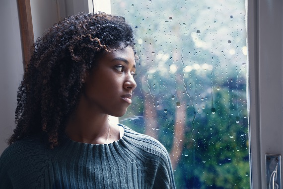woman looking out of a window with a sad expression on her face