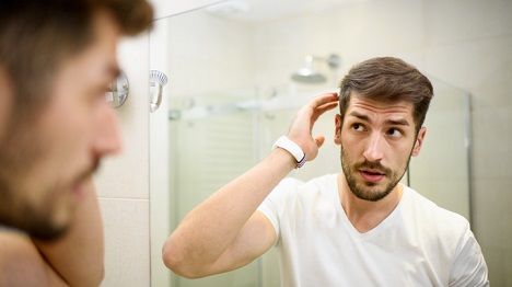 Guy brushing off dandruff from his hair.