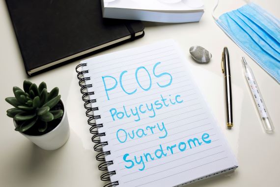 notebook with PCOS polycystic ovary syndrome written in blue ink
