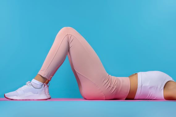 woman in exercise clothes lying on a workout mat