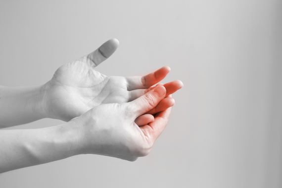 black and white photo of someone touching their fingers, which are red, indicating pain
