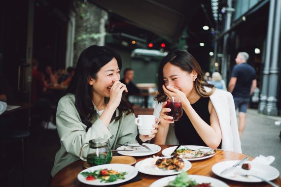 two women having lunch together and laughing