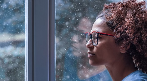 woman with glasses looking out a window
