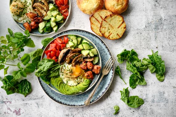 plate with eggs, avocado, tomatoes, cucumbers and side of bread