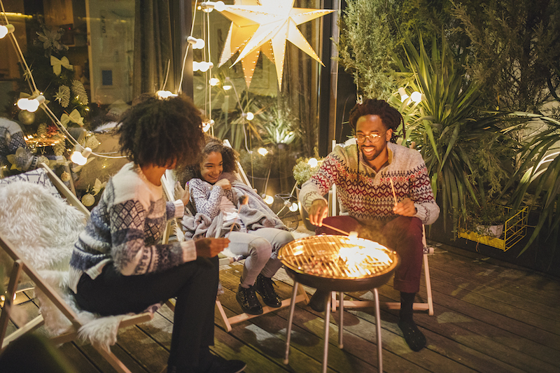 A family roasts marshmallows outside as they celebrate the holidays.