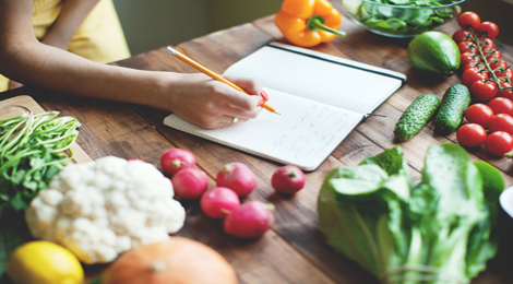 A women counting calories while surrounded by vegetables.