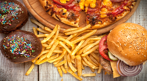 Burgers, fries, cupcakes, and pizza on a table. 