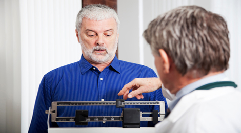 Doctor weighing a male patient.