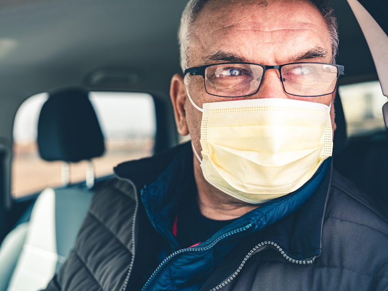 An older man demonstrates the proper way to wear a mask. 