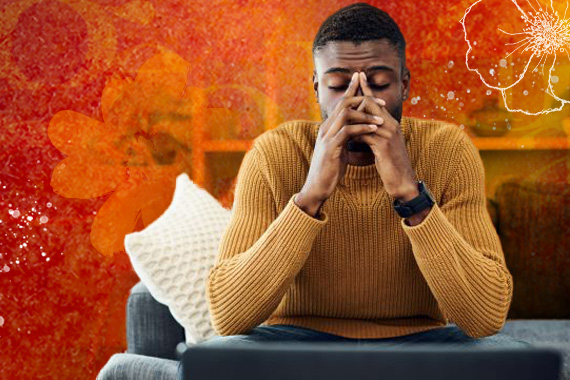 man sitting on couch with hands on his face looking tired