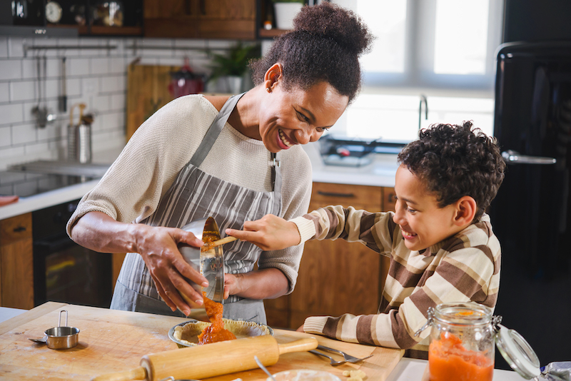 A mother and her child bake pumpkin pie. 