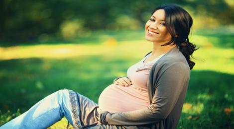 A pregnant woman sitting in her yard.
