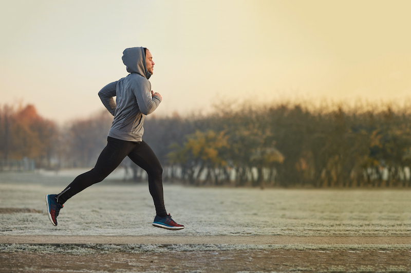 A man jogs outdoors in colder weather.