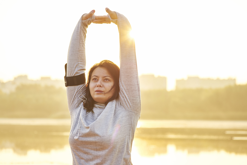 A woman does stretches outdoors in winter. 