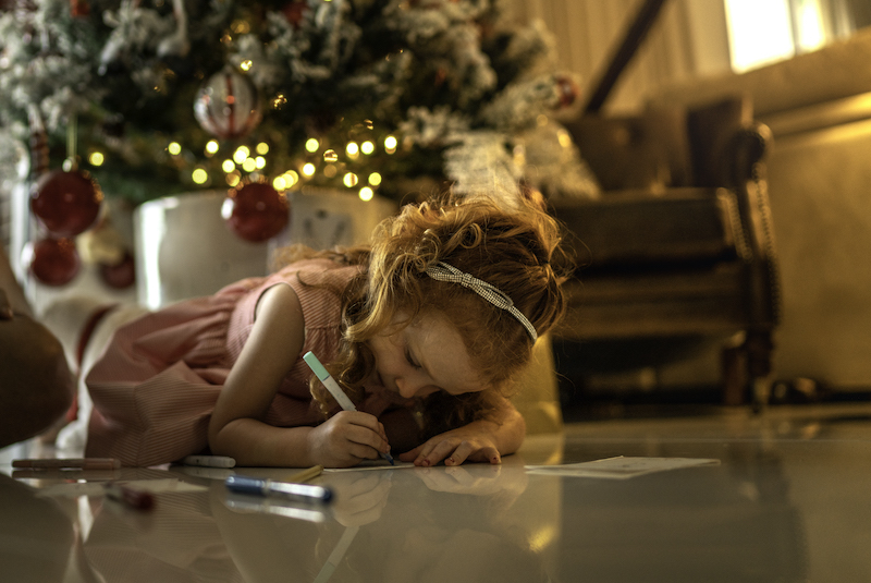 A young girl writes holiday cards in her home. 