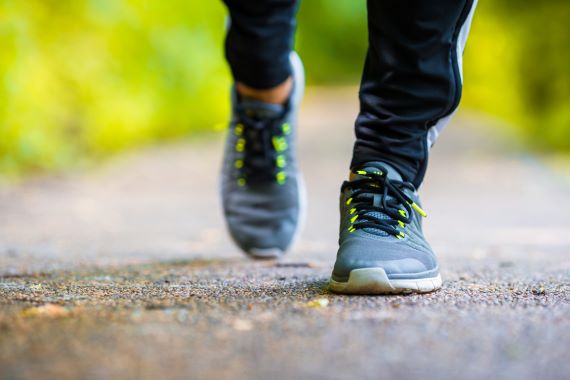 closeup photo of a person walking on a paved trail