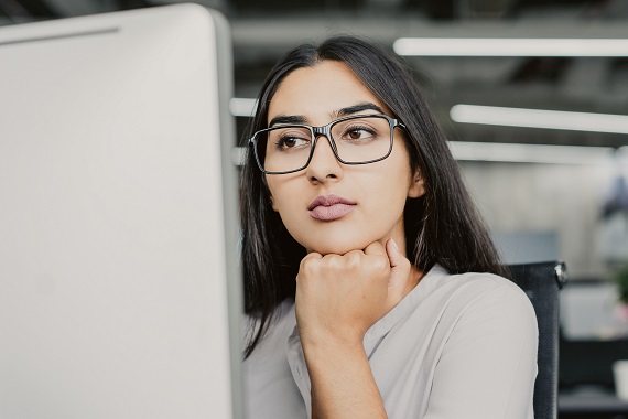 young woman with glasses looking at a computer screen