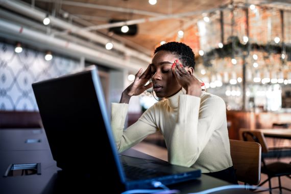 woman looking at laptop with stressed expression on her face