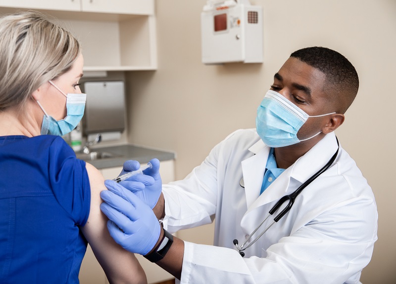 doctor giving healthcare worker the COVID-19 vaccine