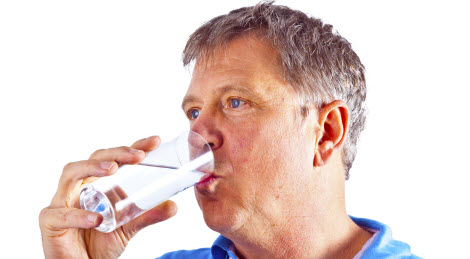 Man drinking water out of a glass.