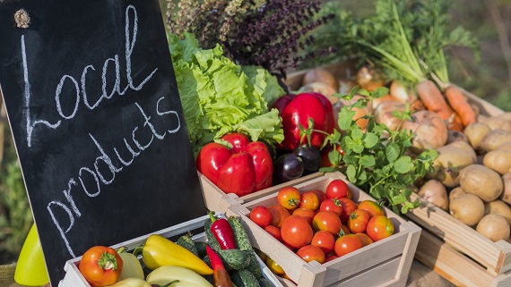 table at the farmers market with fresh produce and a sign that says local products