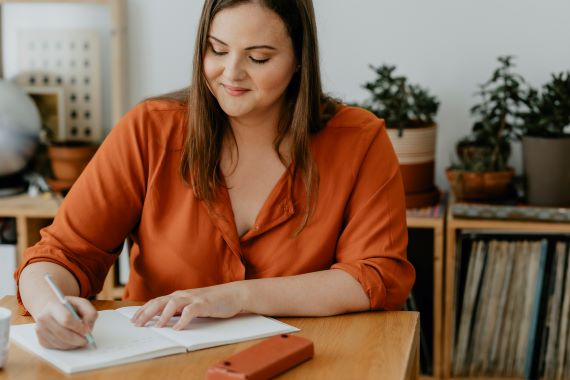 woman sitting at a table writing in a journal