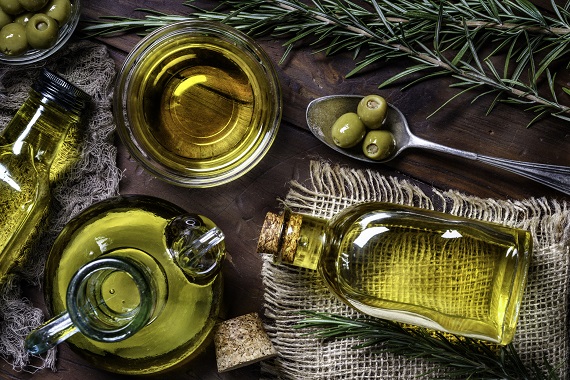 several bottles of cooking oils and olives on a table