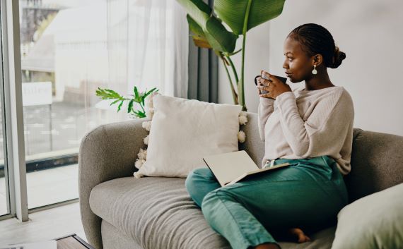 woman sitting on couch with a cup of tea and a journal in her lap