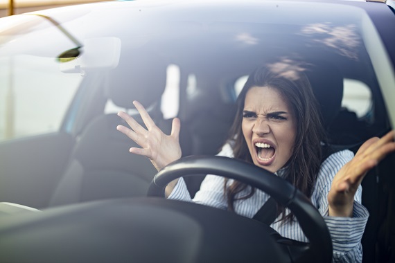 woman sitting in a car and raising her hands in anger