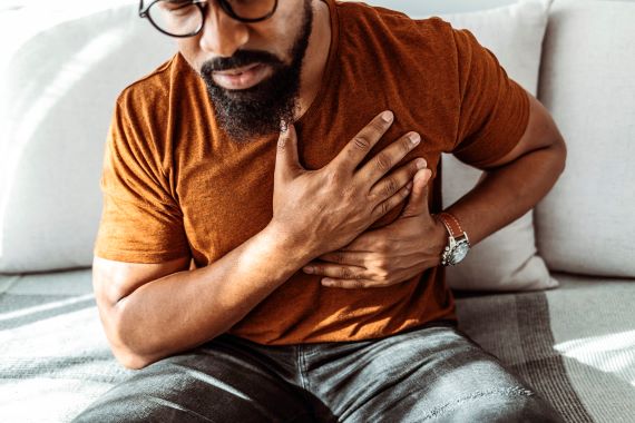 photo of a man leaning forward in pain with his hands on his chest