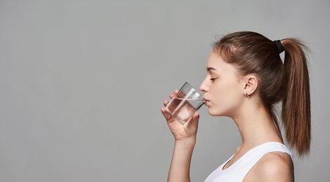 Drinking water out of a glass.