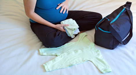 A pregnant woman packing up her maternity bag.