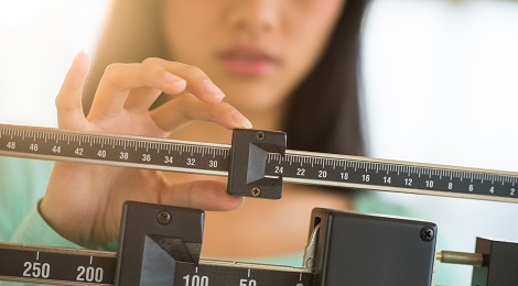 Women checking her weight on a scale.