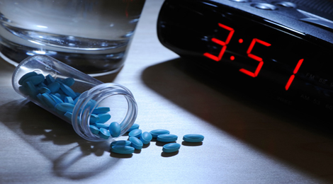 Sleeping pills next to an alarm clock. 