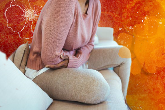 photo of woman clutching her stomach while sitting on a couch