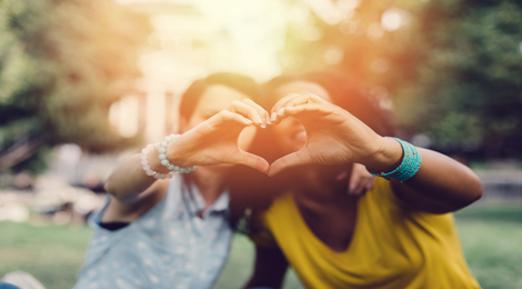 Two girls making heart hands