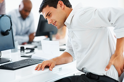 man sitting a desk holding back