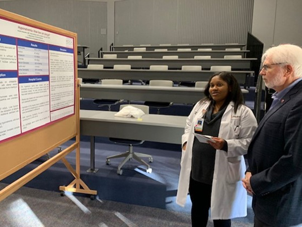 Two people standing in front of a board