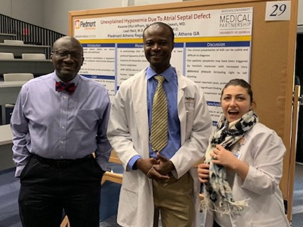 Three people standing in front of a board